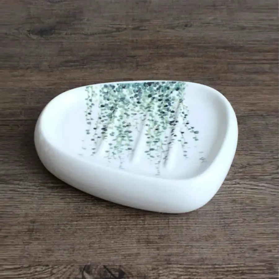 White ceramic bathroom soap dish with a green vine pattern.