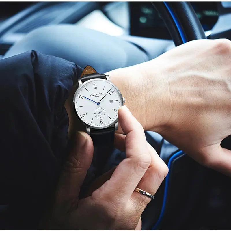 Carnival men's wristwatch with white dial, blue hands, black leather strap in a car interior.