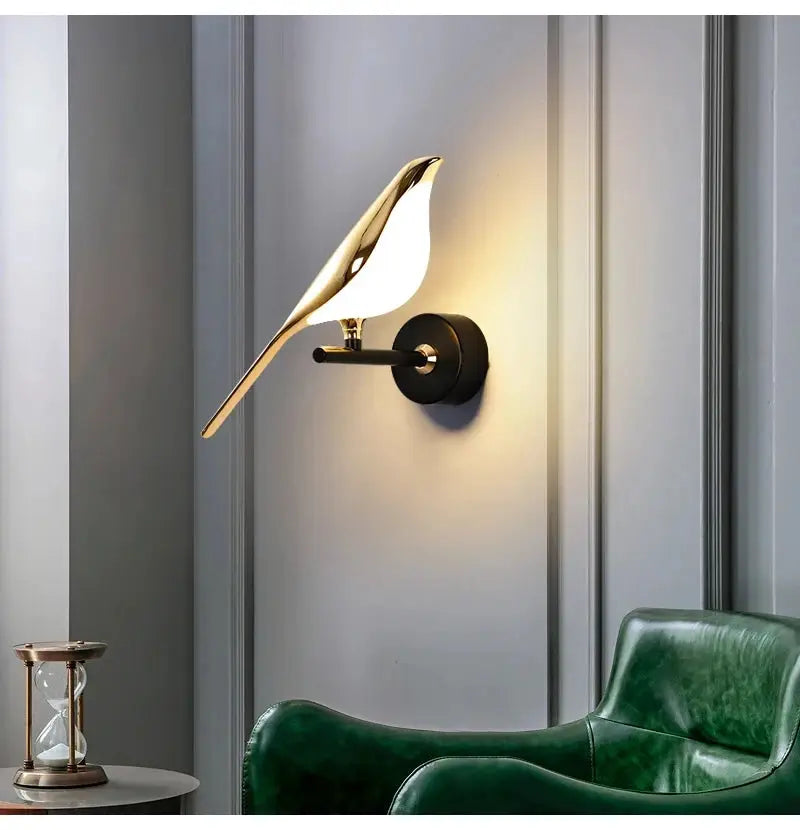 Modern LED wall sconce featuring magpie bird design, white body with gold accents on black mount.