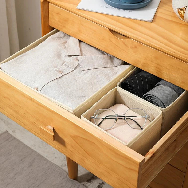 Three beige foldable fabric drawer organizers in a wooden dresser drawer for clothing and socks storage