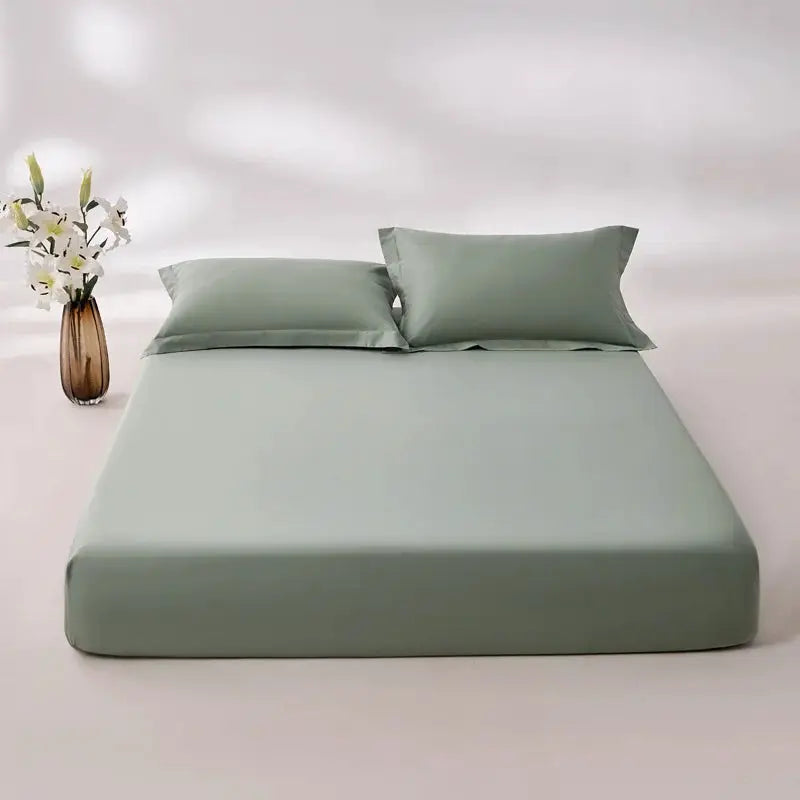 100% Egyptian cotton fitted sheet in sage green with elastic edges on a bed; 2 matching pillows