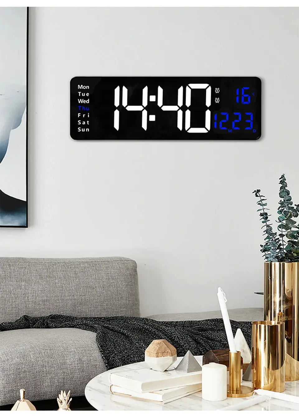 Large digital wall clock with LED white numerals, blue temperature display and weekday indicator, wall-mounted in a living room.
