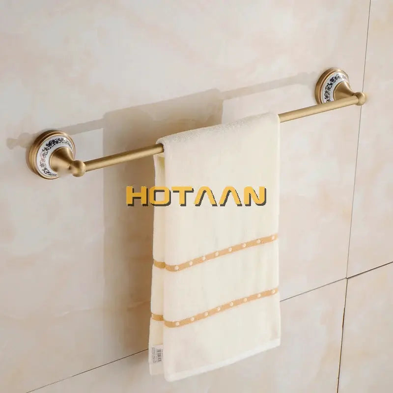 Antique brushed brass towel bar with blue-patterned porcelain mounts and a white towel.