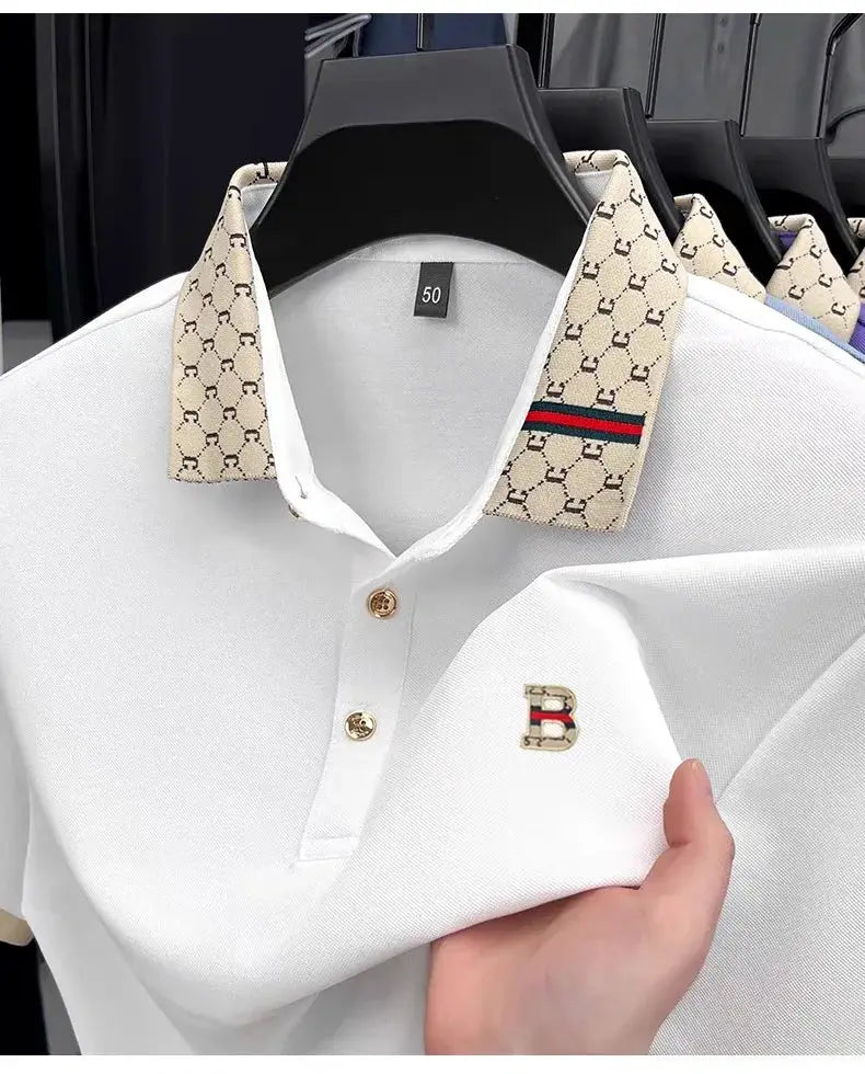 White short-sleeve polo with beige patterned collar, gold buttons, and B monogram embroidery on chest