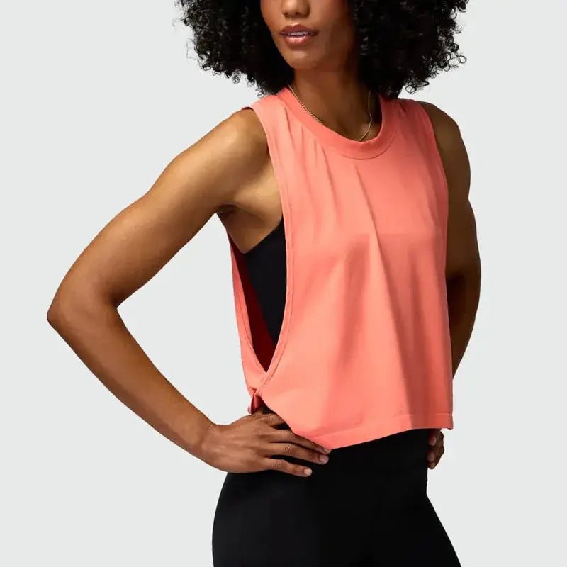 Women coral pink sleeveless running vest crop top; breathable workout tank with black sports bra visible underneath.