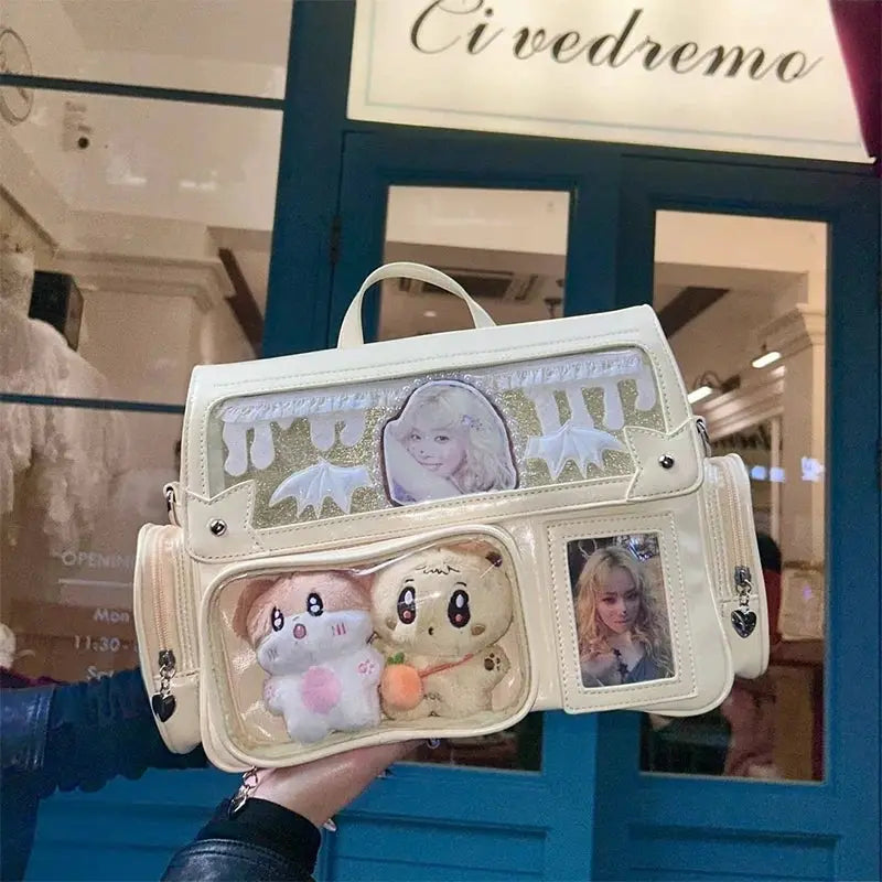 White ita bag with transparent pockets; shows plush toys and a photo card display, crossbody bag