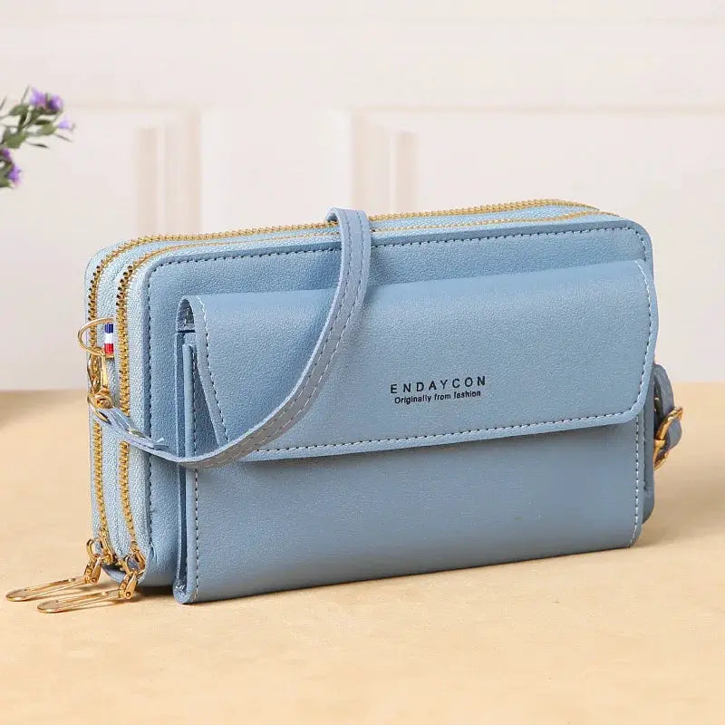 Light blue crossbody bag with front flap, dual gold zippers, ENDAYCON logo