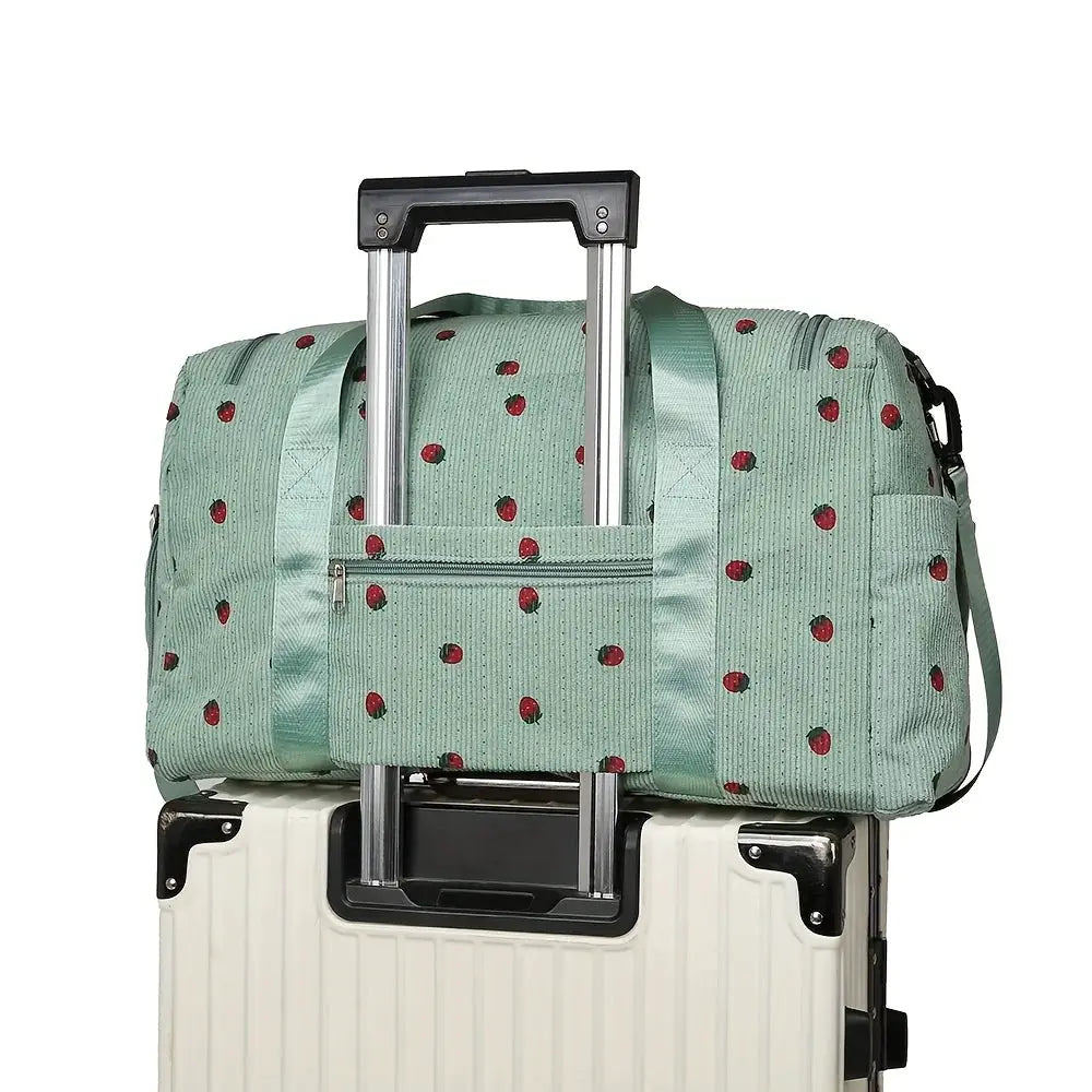 Strawberry travel bag by Simples Market, mint green corduroy luggage bag with red berry prints atop a white suitcase