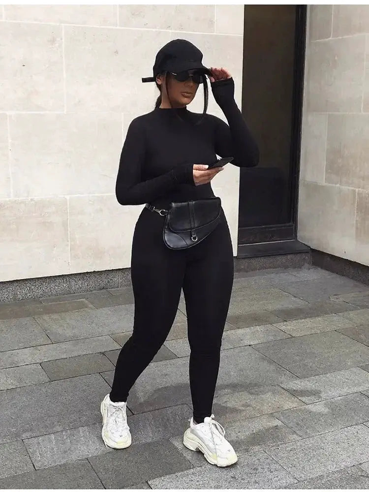Women's solid black long-sleeve skiing jumpsuit with elastic fit and waist belt bag