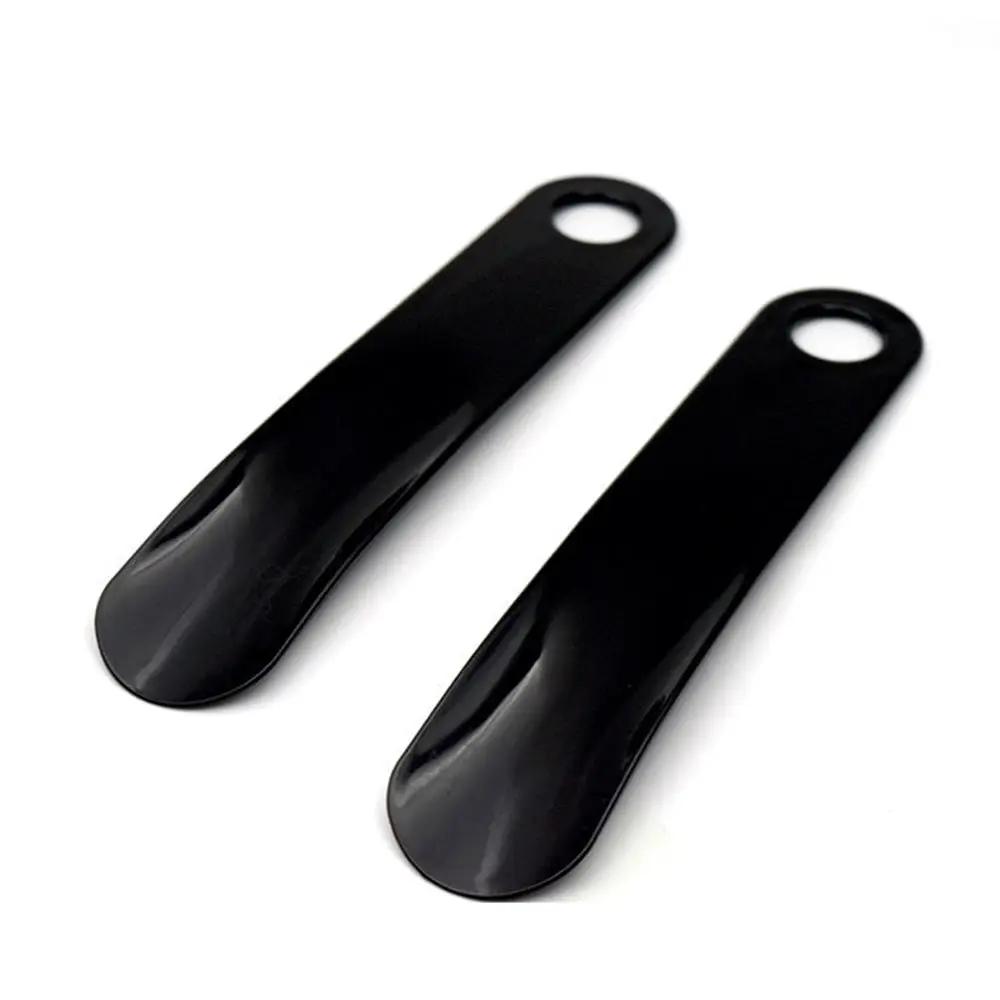 Pair of black plastic spoon-shaped shoe horns with hanging holes.