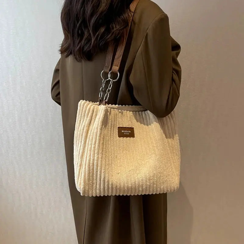 Women corduroy shoulder bag by Simples Market; beige textured bag with fixed brown strap and metal rings.
