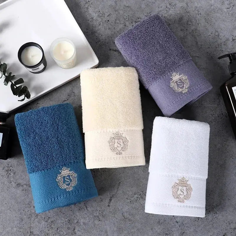 4-piece cotton towel set in blue, cream, purple and white with an embroidered crest