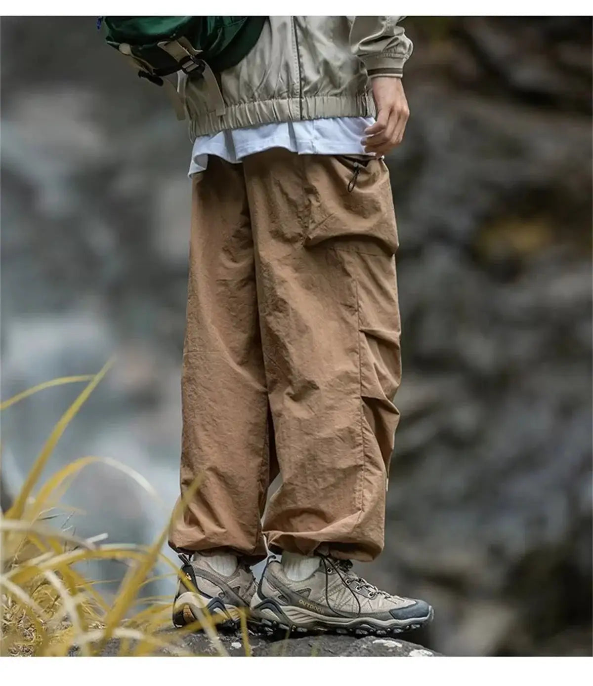 Men's tan cargo mountaineering pants with waterproof fabric and zip pockets, paired with hiking boots