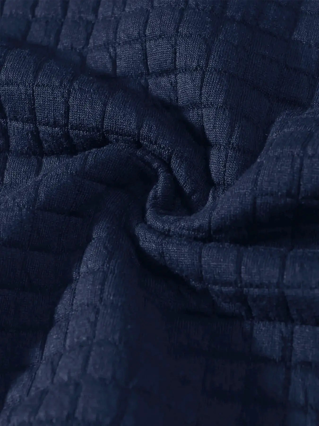 Men's navy knit pullover fabric close-up with quilted grid texture