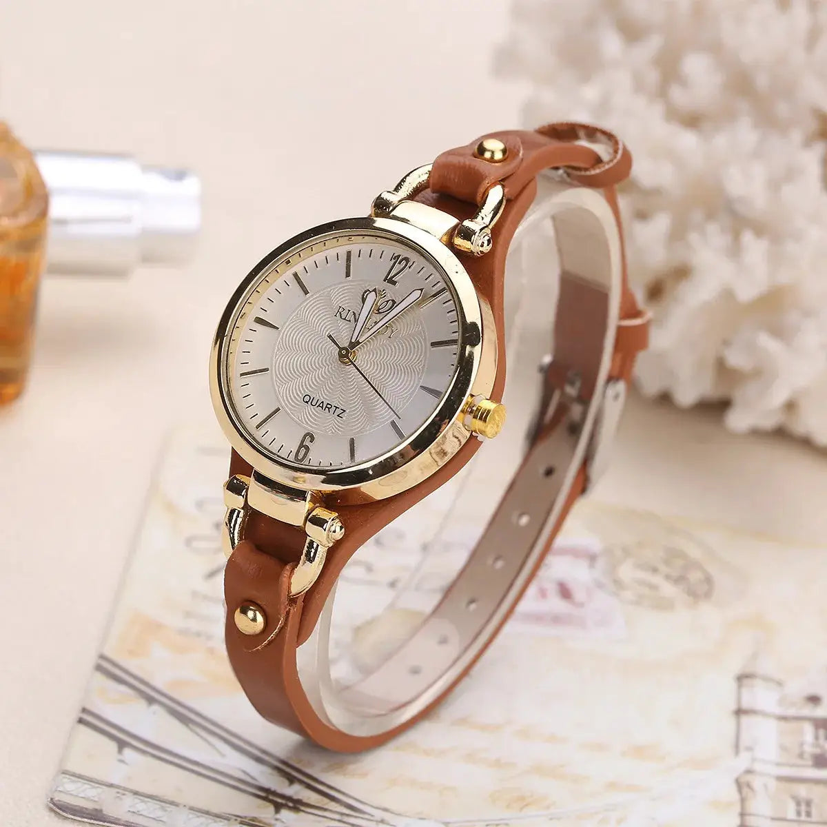 Women's leather-strap quartz watch with a gold-tone case and silver dial.