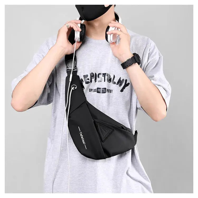 Black sling chest bag worn across the chest; compact anti-theft crossbody phone bag for men.