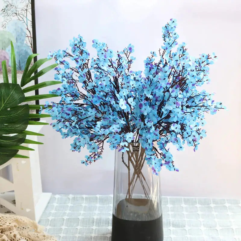 Artificial blue cherry blossom gypsophila bouquet in a clear glass vase with black base