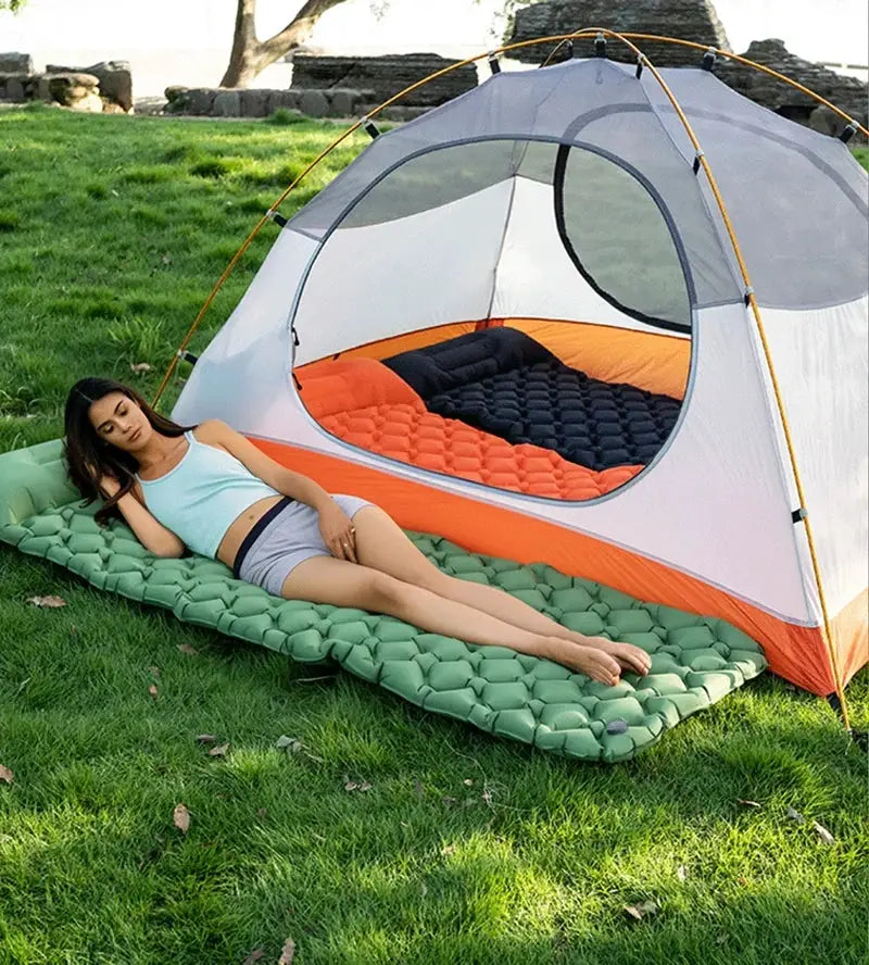 Inflatable mattress sleeping pad Simples Market, green with orange edge, laid beside a camping tent on grass