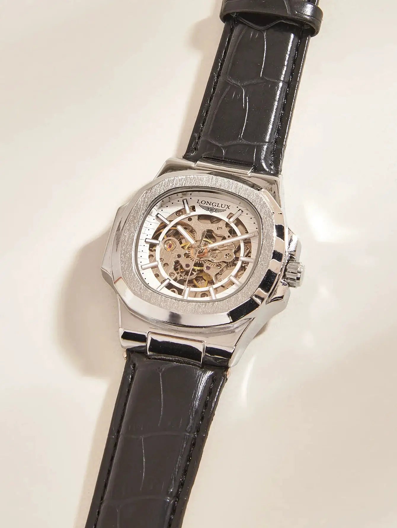 Men's skeleton automatic watch with silver case and black leather strap, visible gears, Longlux on dial.