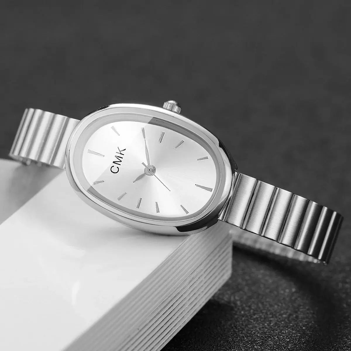 Women's oval-dial wristwatch with silver metal link band and CMK logo on dial