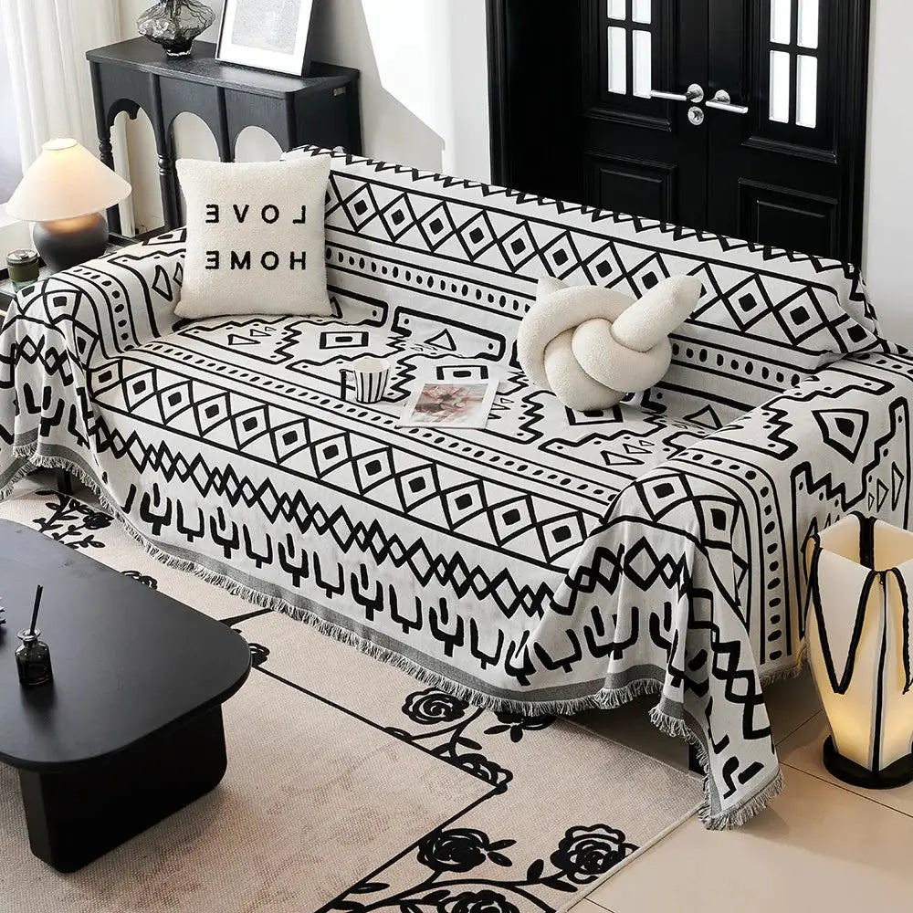 Sofa towel blanket in cream with black geometric print and fringed edges on a sofa