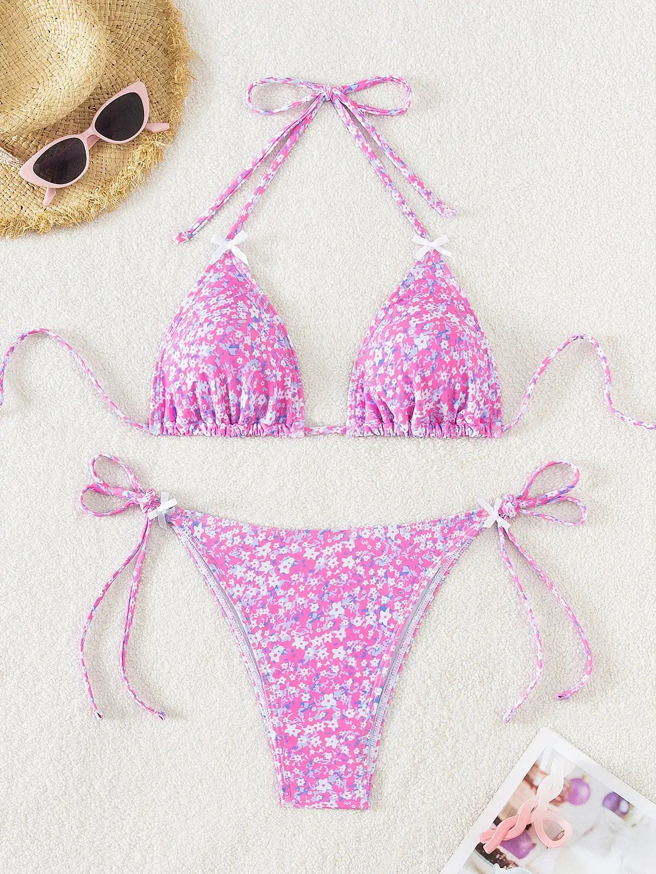 Women's pink floral bikini set with adjustable tie sides and triangle top on sandy beach