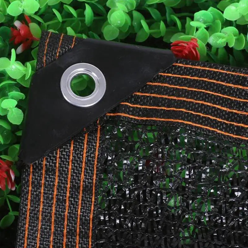 HDPE sun shade net for outdoor plants; black with orange stitching and a metal grommet corner