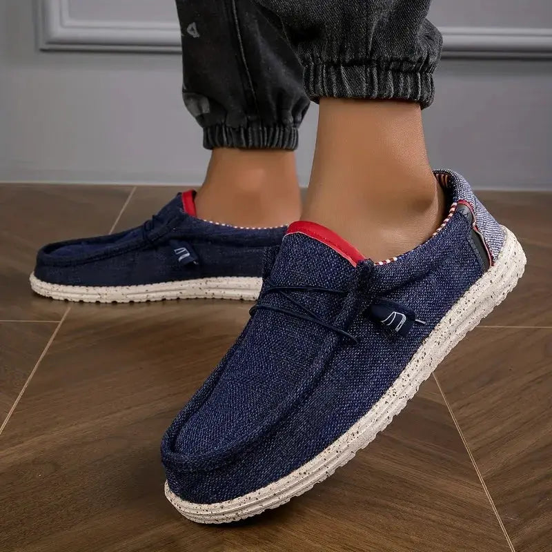 Pair of men's navy canvas loafers with red trim and white textured sole.