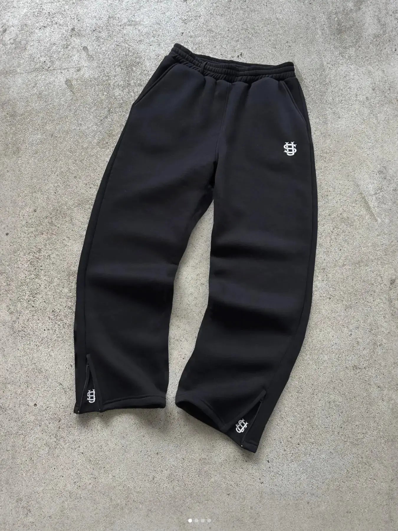 Black joggers by Simples Market with white logo embroidery on thigh and cuffs, elastic waistband.