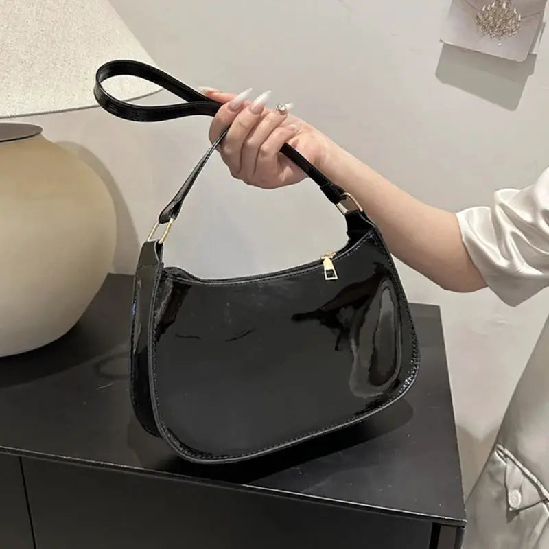 Shoulder bag black patent PU leather with gold hardware and top handle.