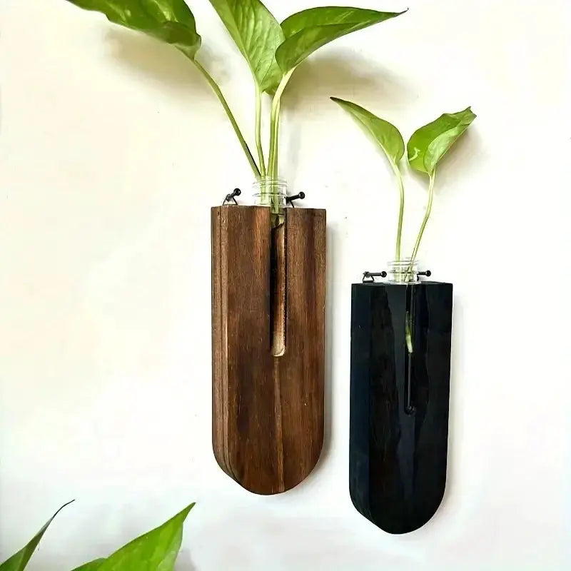 Two wooden hanging wall planters in brown and black with glass jars and green plant stems