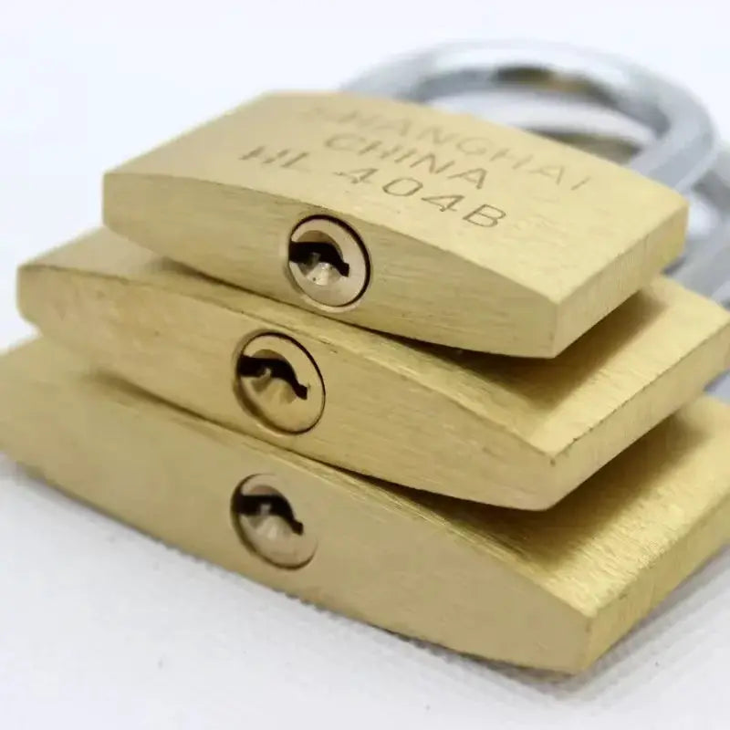 Three brass padlocks with keys, stacked together; small luggage/locker locks