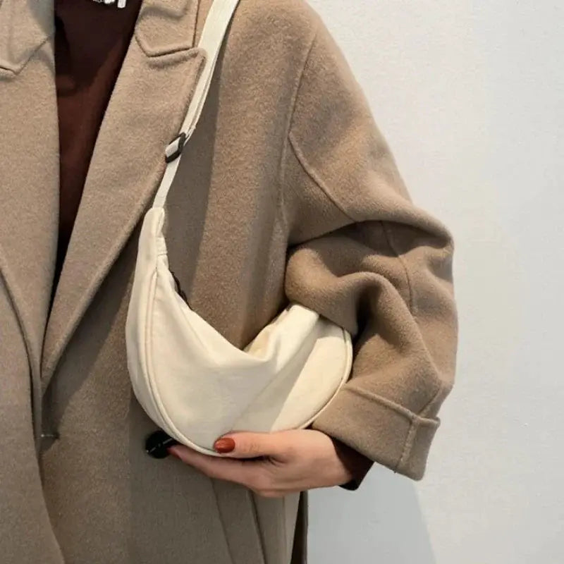 Nylon dumpling bag by Simples Market, small cream crossbody shoulder bag with a curved crescent shape.