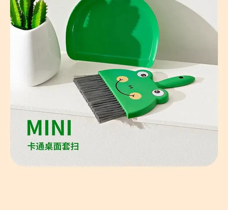 Mini cartoon desktop broom with green frog-face handle for compact desk cleaning.