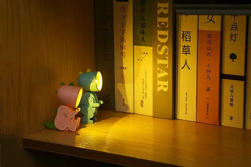 Mini Night Light LED Cartoon Hero Police lamp, pink and teal figures, warm glow on wooden shelf beside books, 2pcs.