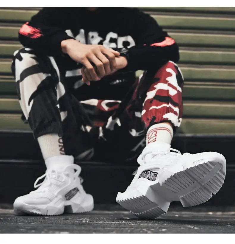Pair of men's white athletic sneakers with chunky, ridged outsole and breathable upper.