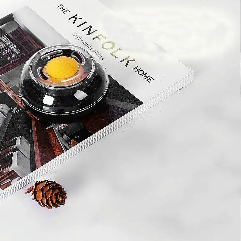 Round black plastic money-counting tool with a clear lid and yellow center on a Kinfolk Home magazine.