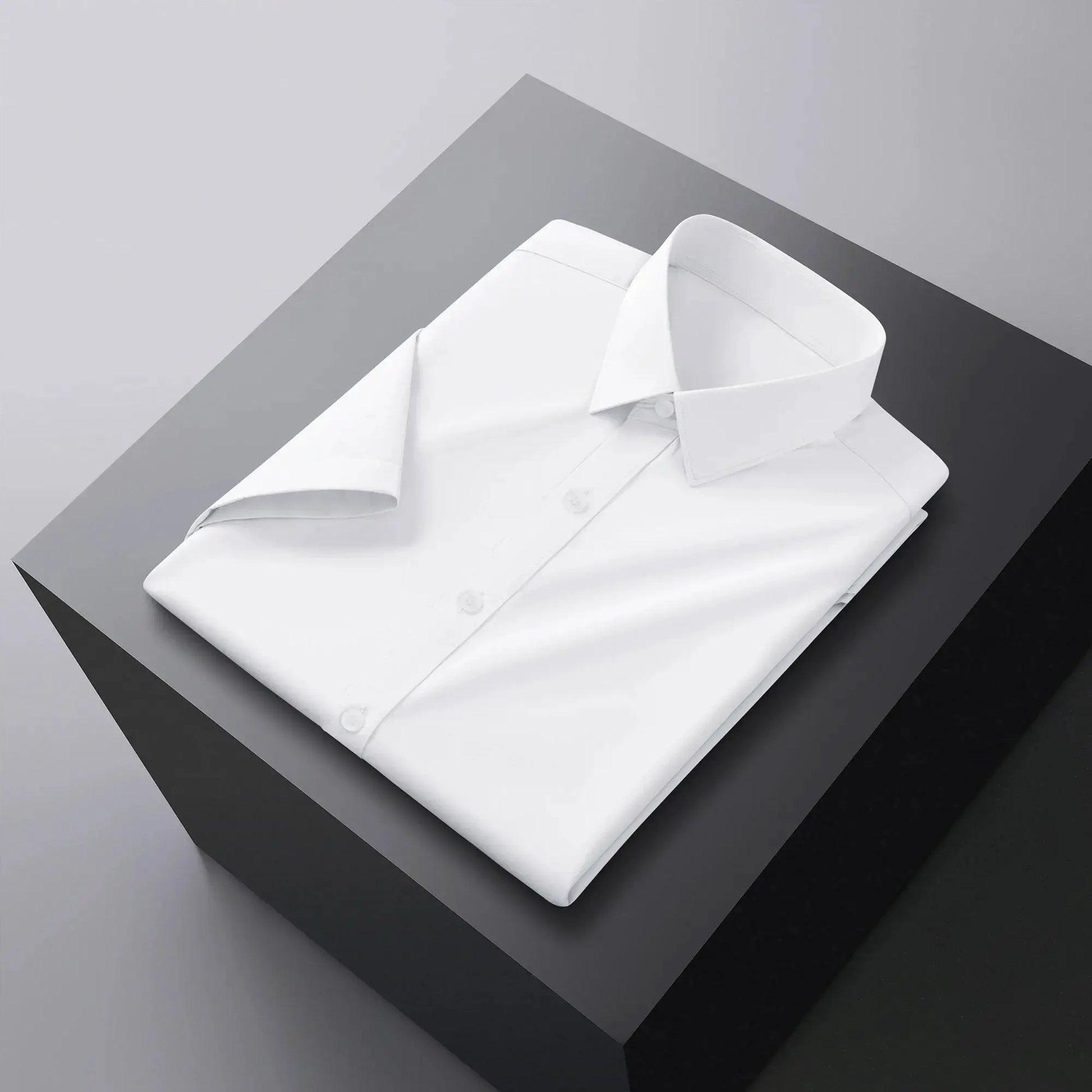 Men's white dress shirt by Simples Market, neatly folded on gray geometric backdrop.