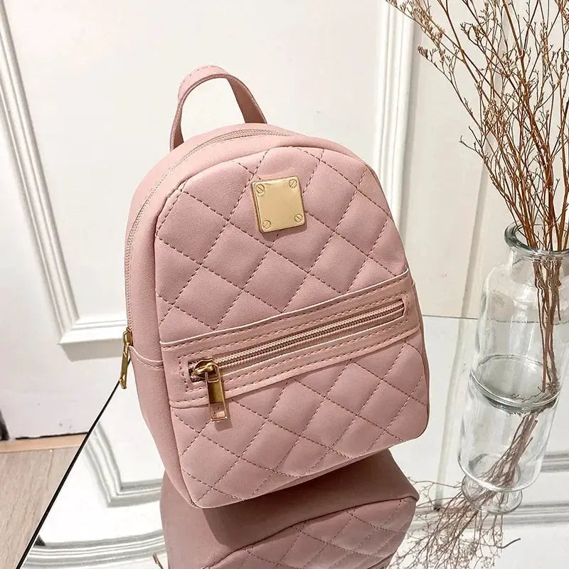 Pink quilted mini backpack with gold zippers and a top handle.