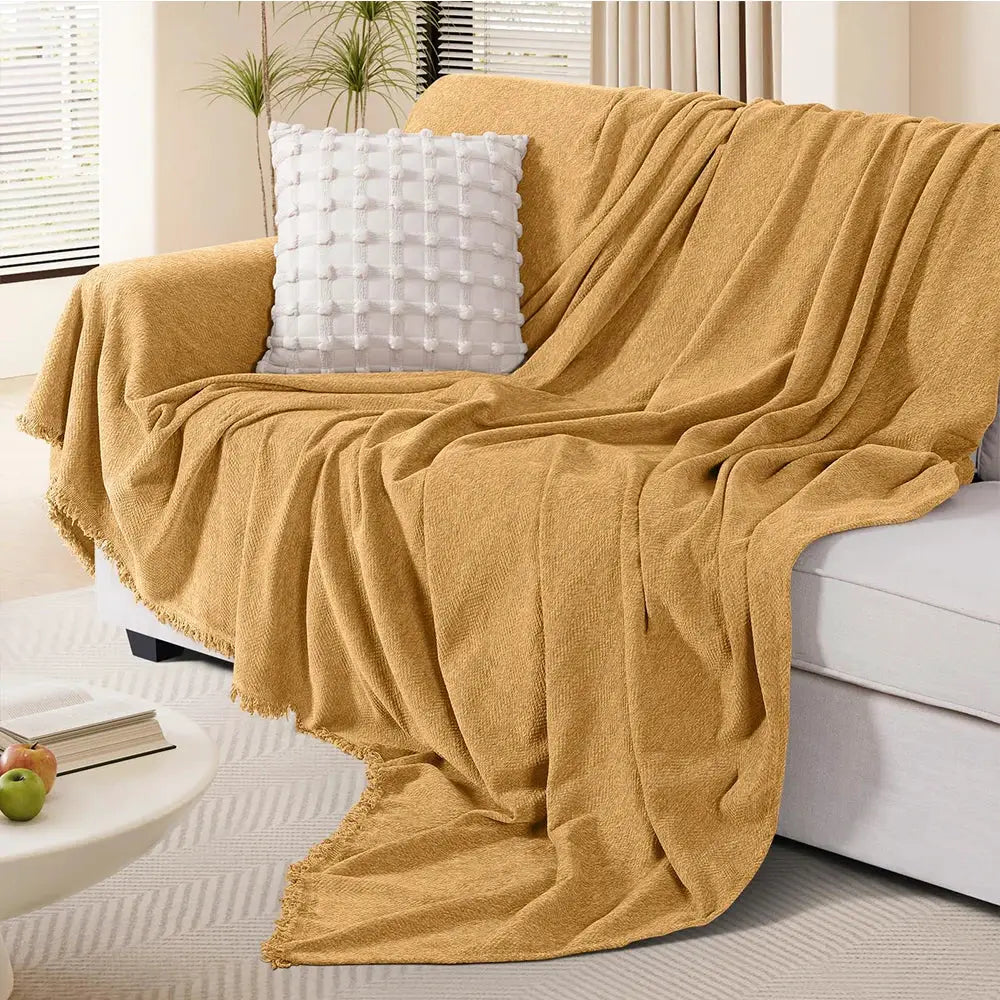 Couch cover by Simples Market in mustard chenille with fringe on a white sofa.