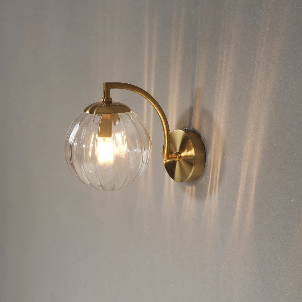 Modern LED wall lamp with glass globe shade in brass finish from Simples Market