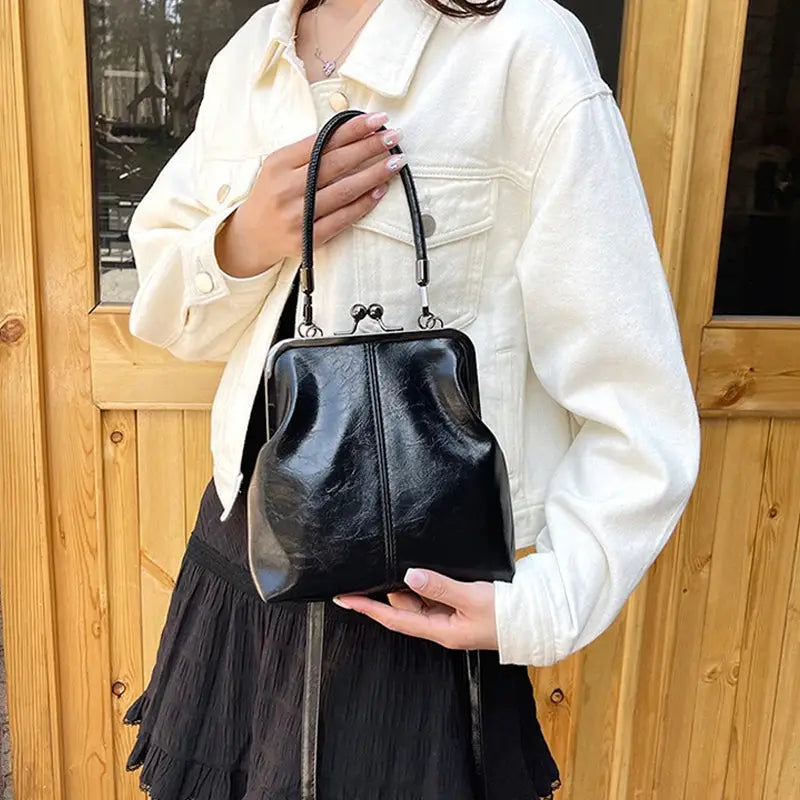 Vintage-style women's handbag in black PU leather with a metal frame clasp and short top handle.