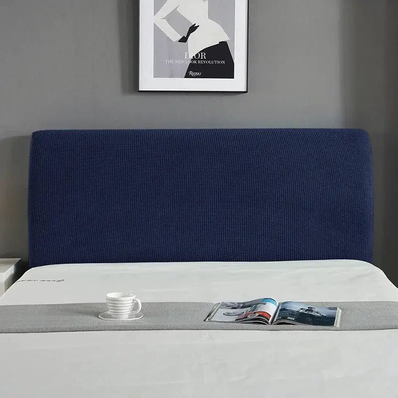 Bed headboard cover in navy blue elastic fabric on a white bed with a gray bed runner