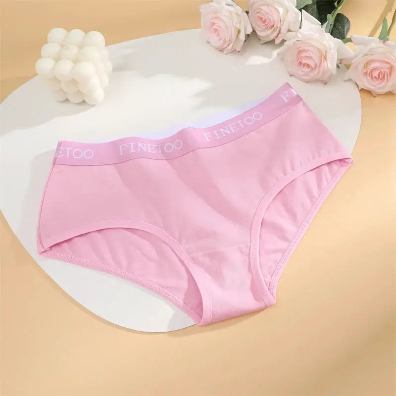 Pink cotton women's briefs with FINETOO waistband, breathable stretchy underwear on a white round table.