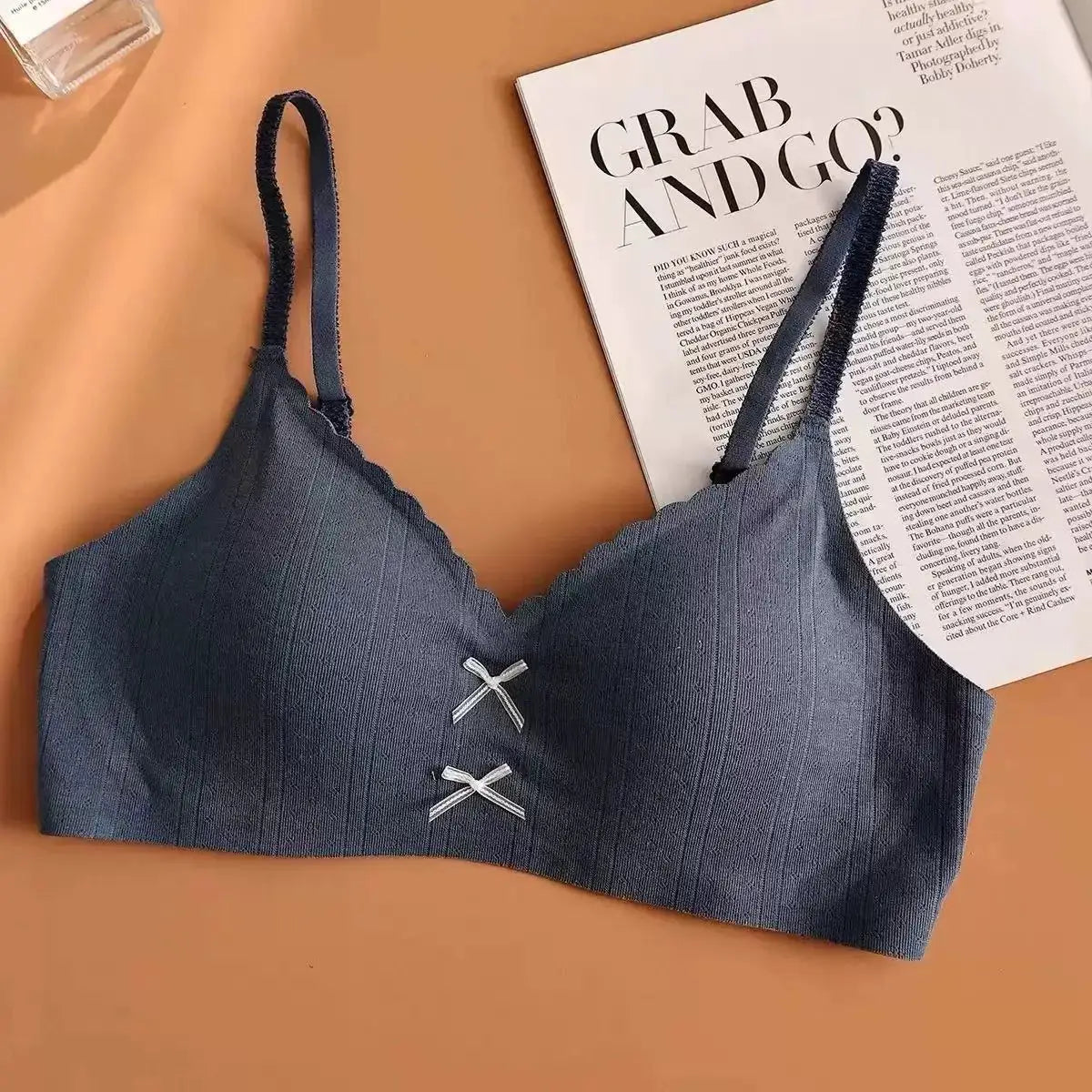 Women's navy blue gathered sports bra with thin straps and small front bows.