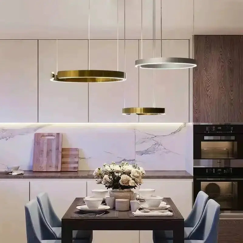 Nordic Ring LED pendant lamps; three hanging rings in gold and silver over a modern dining table