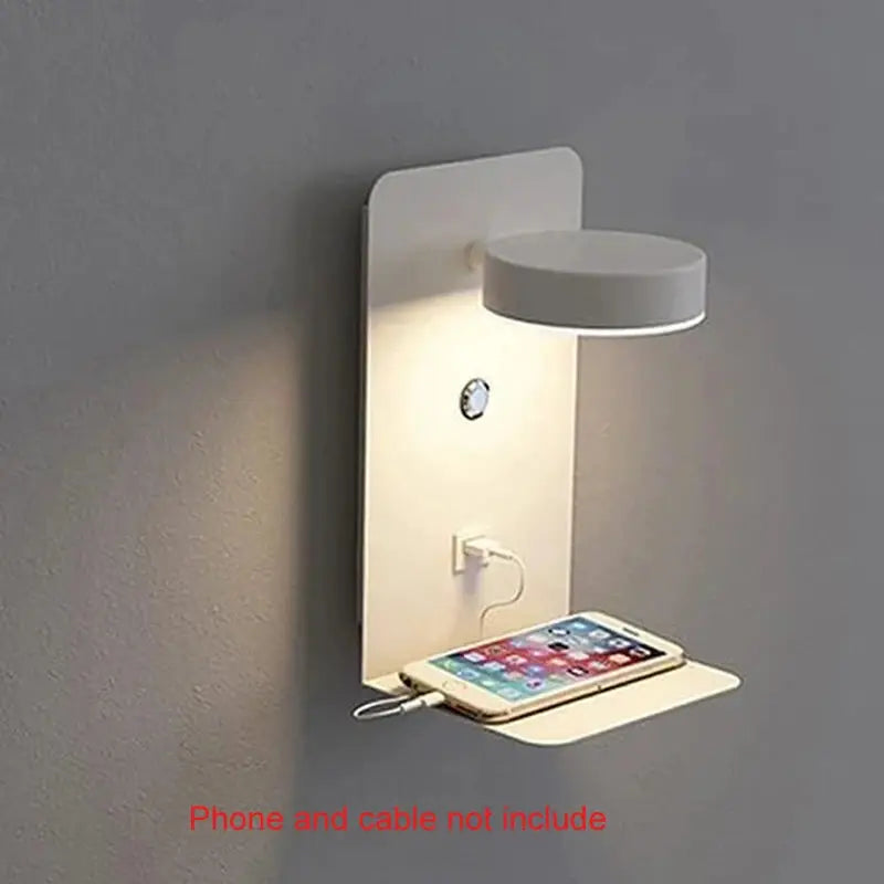 LED wall lamp sconce in white with built-in shelf and USB charging; phone rests on shelf.