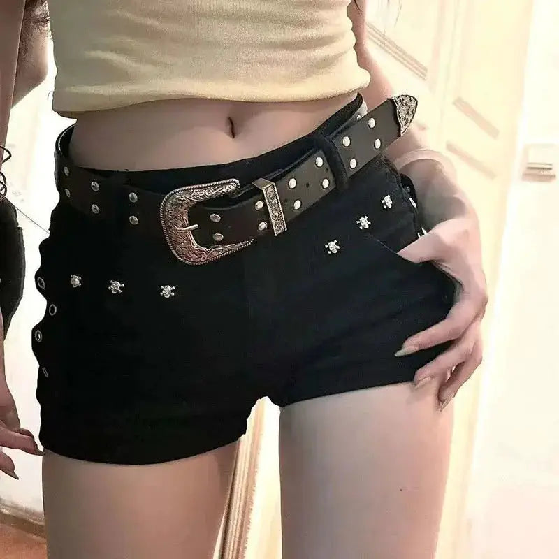 Black low-waist denim shorts with silver stud embellishments and a wide studded belt.