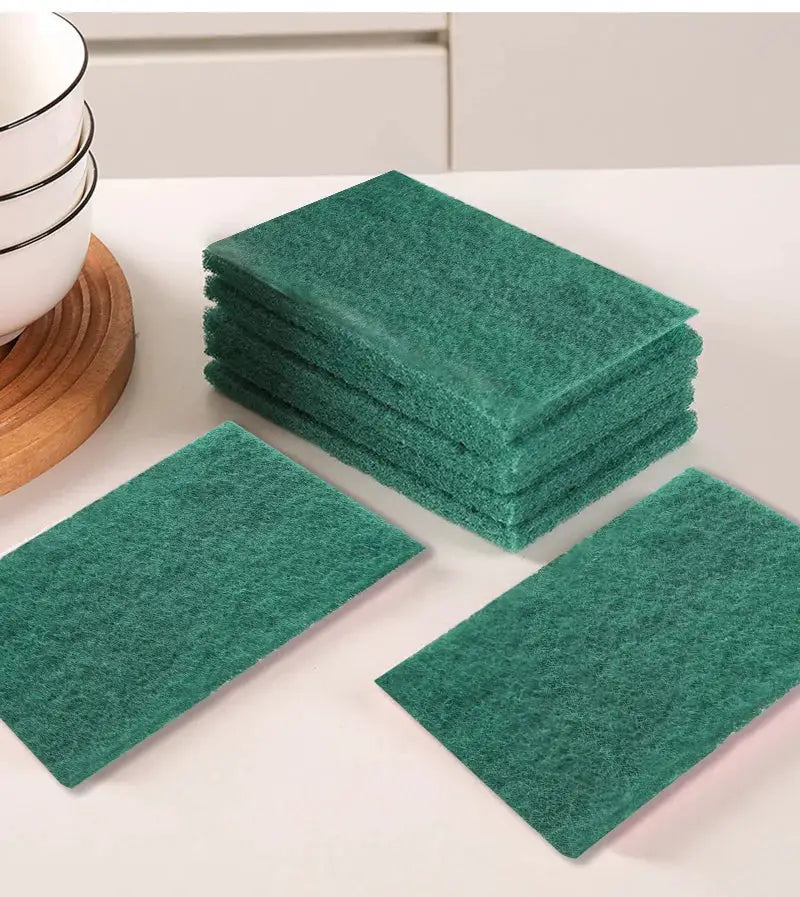 Green kitchen scrub pads; stack of reusable abrasive pads on a white countertop.