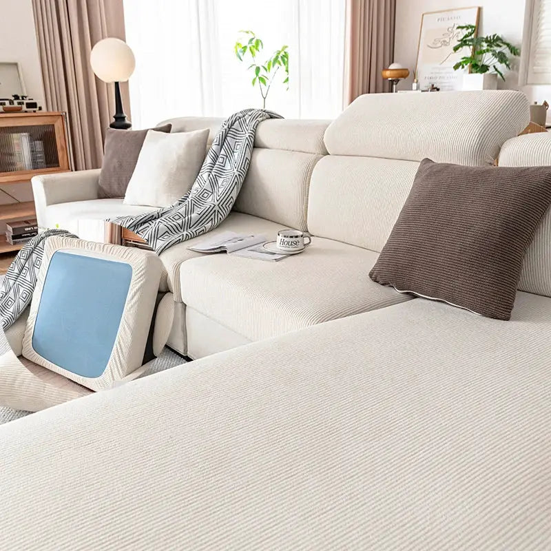 Simples Market beige plush sofa cover on a cream living-room sofa with pillows and a geometric throw.